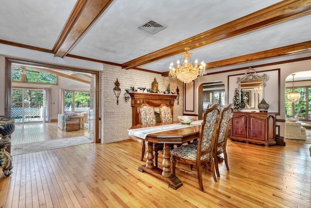 dining area with beamed ceiling, brick wall, a notable chandelier, light wood-type flooring, and ornamental molding