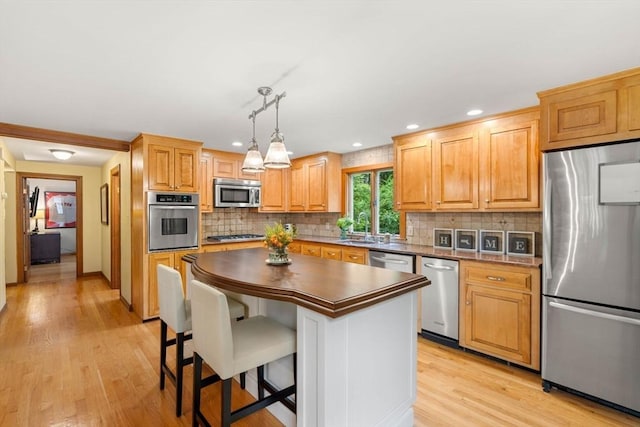 1857 Great Pond Rd, North Andover, MA 01845 - kitchen with appliances with stainless steel finishes, light wood-style floors, backsplash, a breakfast bar, and recessed lighting