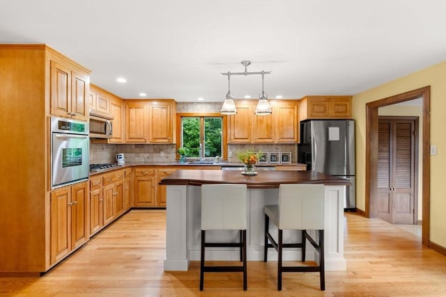 1857 Great Pond Rd, North Andover, MA 01845 - kitchen with appliances with stainless steel finishes, light wood-style floors, backsplash, a kitchen island, and recessed lighting