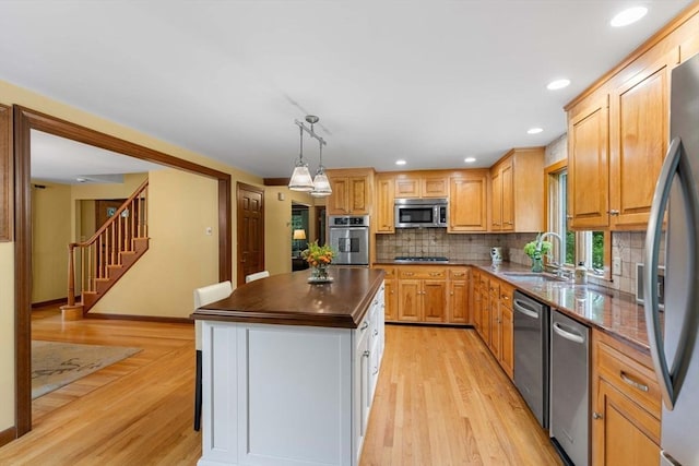 1857 Great Pond Rd, North Andover, MA 01845 - kitchen featuring appliances with stainless steel finishes, dark countertops, light wood-style floors, backsplash, and a center island