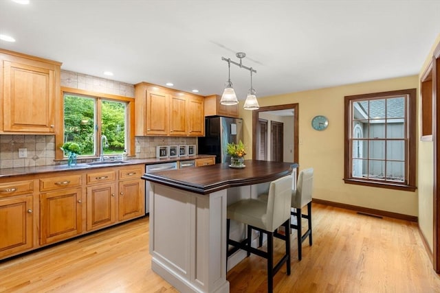 1857 Great Pond Rd, North Andover, MA 01845 - kitchen featuring stainless steel appliances, dark countertops, tasteful backsplash, a kitchen breakfast bar, and light wood-style floors