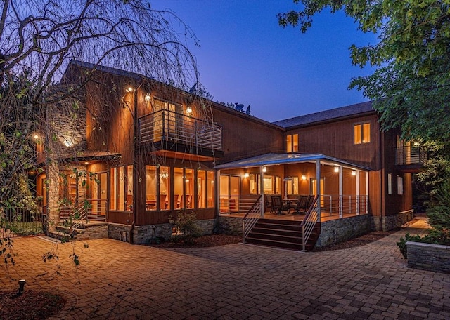 back house at dusk with a balcony