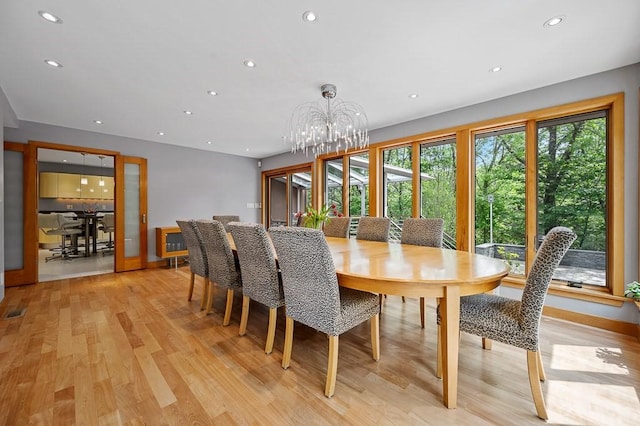 dining area with an inviting chandelier and light hardwood / wood-style flooring