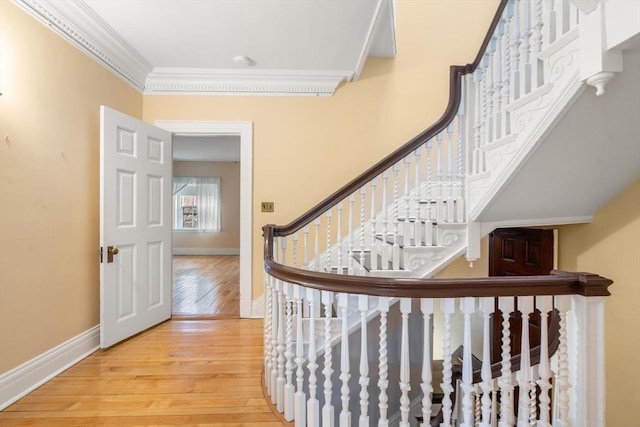 stairway with wood-type flooring, crown molding, and baseboards