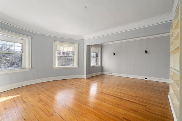 empty room with ornamental molding, light wood-style flooring, and baseboards