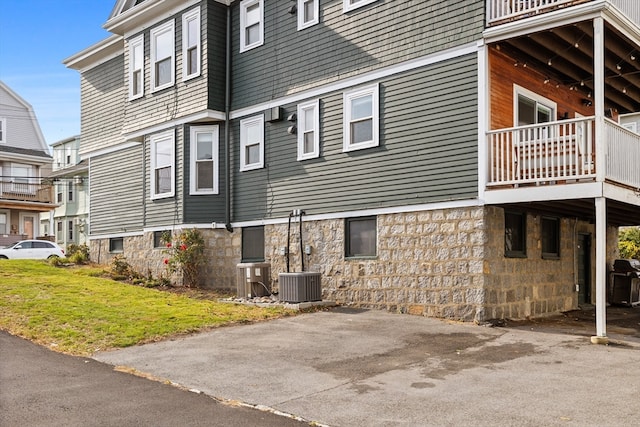 view of side of property featuring cooling unit and a balcony