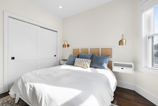 bedroom with multiple windows, a closet, and dark wood-type flooring