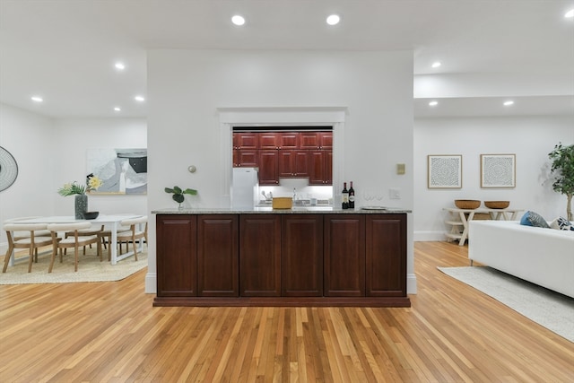 kitchen featuring light stone counters, light hardwood / wood-style floors, and white fridge