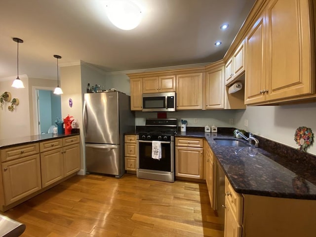 kitchen featuring crown molding, appliances with stainless steel finishes, a sink, a peninsula, and light wood-style floors