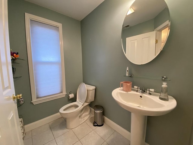 half bathroom featuring toilet, baseboards, and tile patterned flooring