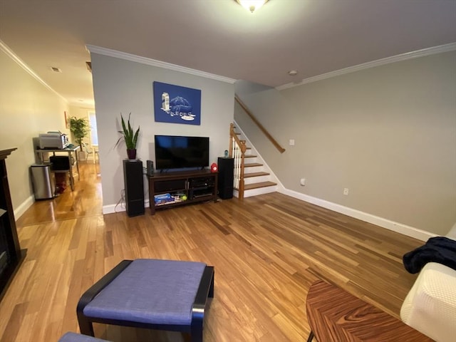 living room with crown molding, baseboards, stairs, and light wood-style floors