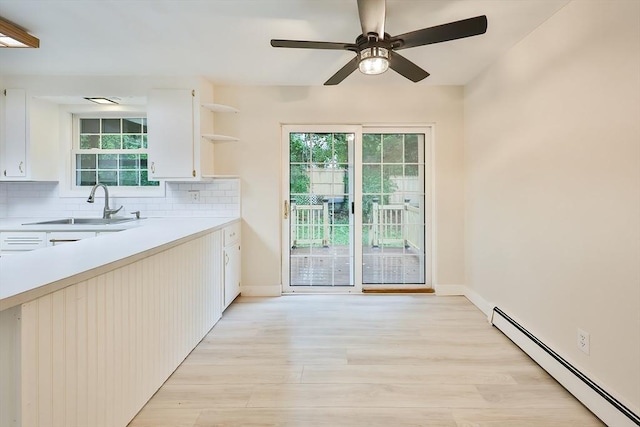 118 Coolidge St, Swansea, MA 02777 - kitchen with a baseboard heating unit, open shelves, light countertops, light wood-type flooring, and tasteful backsplash