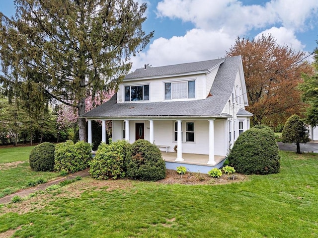 farmhouse featuring a porch, roof with shingles, and a front lawn
