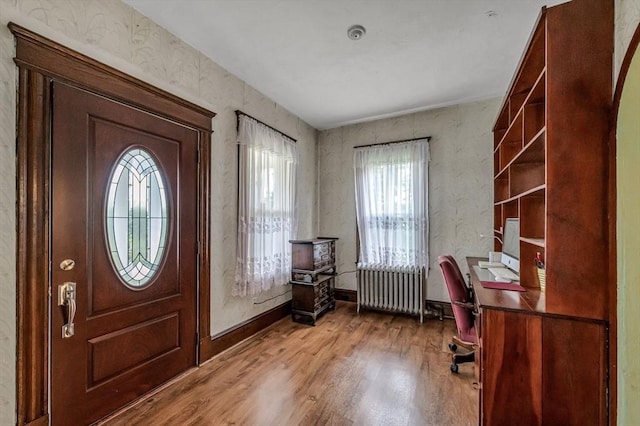 foyer with radiator, baseboards, and wood finished floors