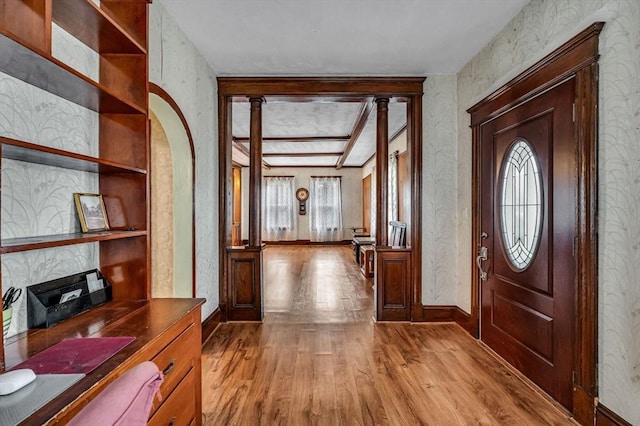 foyer entrance with light wood-type flooring, baseboards, and arched walkways