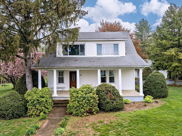 view of front of home featuring covered porch, roof with shingles, and a front yard