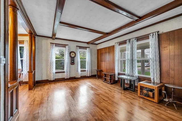 interior space with baseboards, beamed ceiling, ornamental molding, and wood finished floors