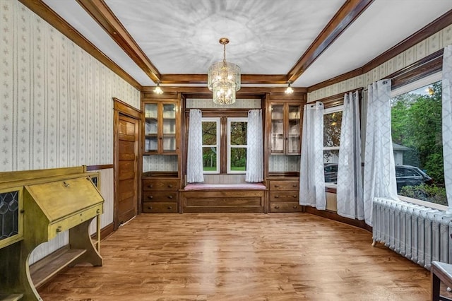 interior space featuring wallpapered walls, radiator heating unit, a chandelier, crown molding, and wood finished floors