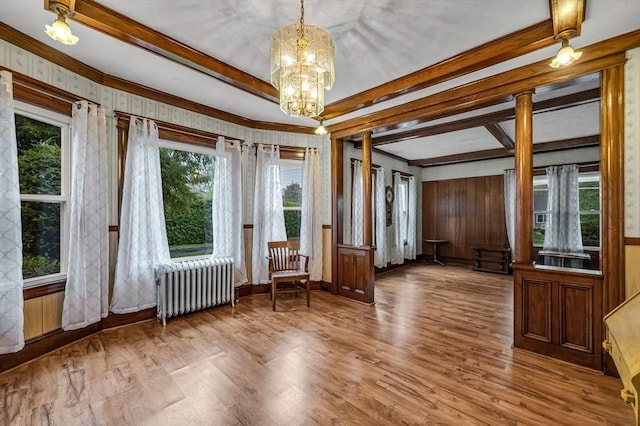 interior space with radiator, wood finished floors, crown molding, a chandelier, and beamed ceiling