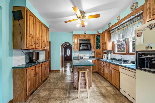 kitchen featuring dark countertops, brown cabinetry, and white appliances