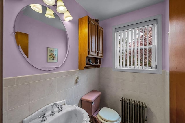 half bath featuring toilet, radiator, tile walls, and a sink