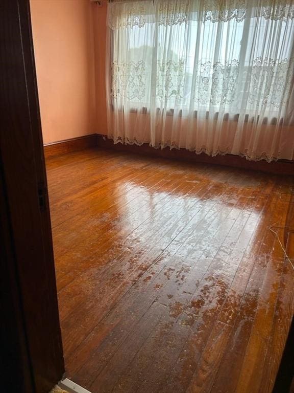 spare room with wood-type flooring and baseboards