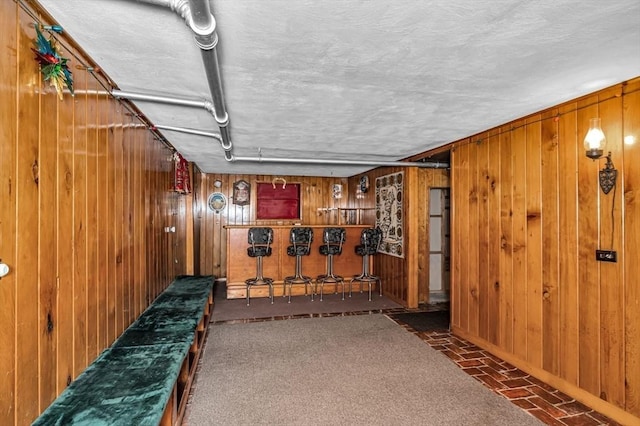 finished below grade area featuring wooden walls, brick floor, and baseboards