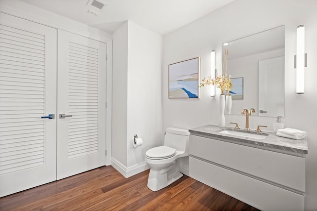 bathroom with hardwood / wood-style flooring, vanity, and toilet