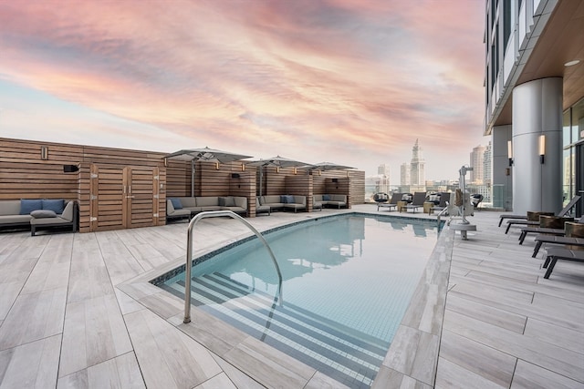 pool at dusk featuring an outdoor living space and a patio area