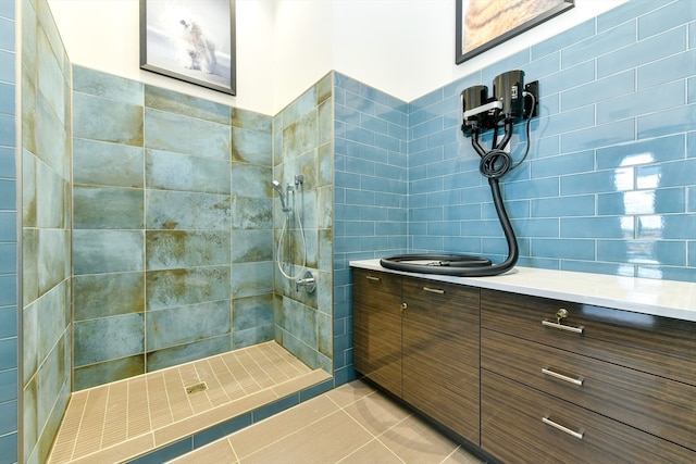 bathroom with tile patterned floors, vanity, and a tile shower