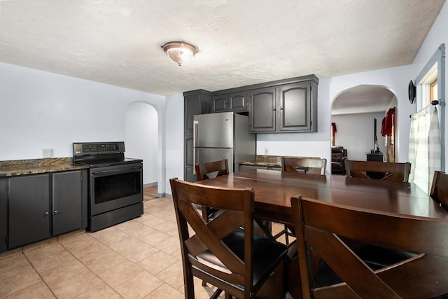 24 Webber Rd, Brookfield, MA 01506 - kitchen with arched walkways, range with electric stovetop, freestanding refrigerator, light tile patterned floors, and a textured ceiling