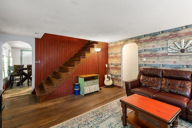 24 Webber Rd, Brookfield, MA 01506 - living room with arched walkways, wood finished floors, stairs, wood walls, and a textured ceiling