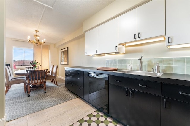kitchen with dishwasher, dark cabinets, white cabinets, a sink, and a chandelier