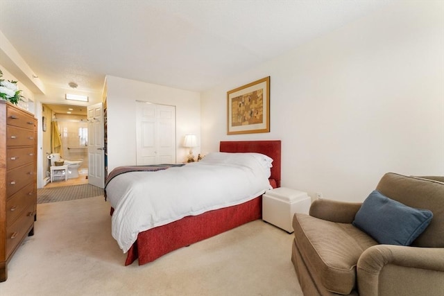 bedroom with light colored carpet, a closet, and ensuite bathroom