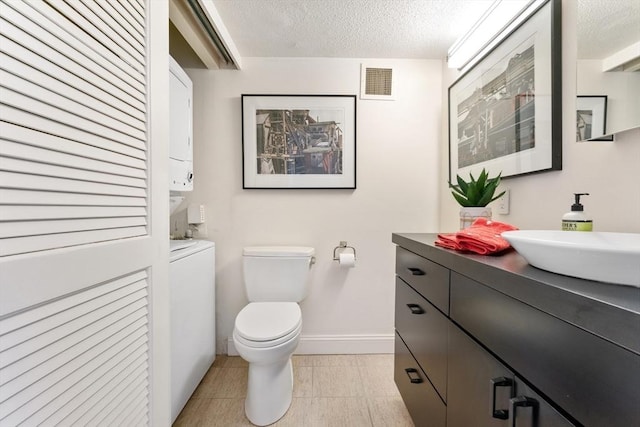bathroom with toilet, a textured ceiling, vanity, and baseboards