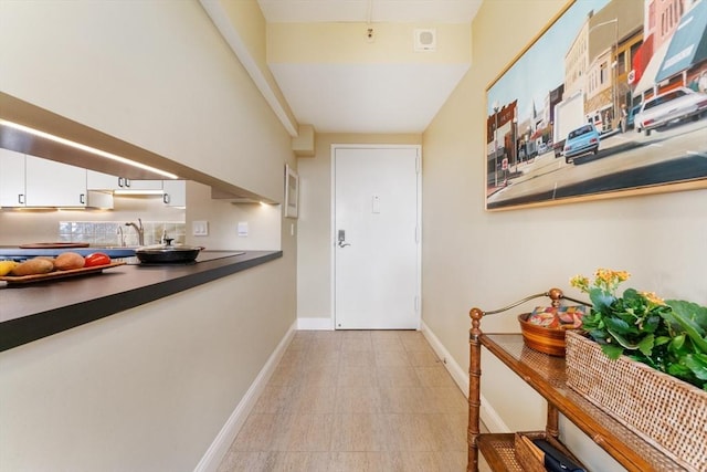 doorway with baseboards and a sink