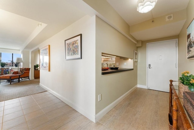 hallway with baseboards and light tile patterned floors