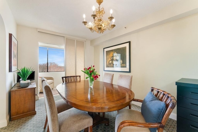 dining room with a chandelier, baseboards, and carpet flooring