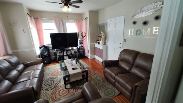 living room with a ceiling fan, baseboards, and wood finished floors