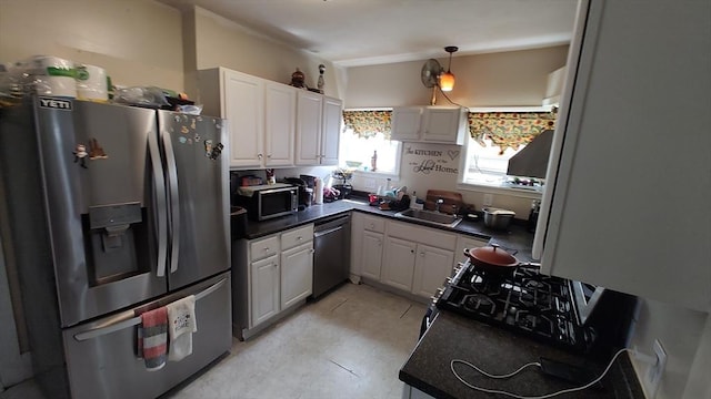 kitchen featuring hanging light fixtures, a sink, dark countertops, stainless steel appliances, and white cabinets
