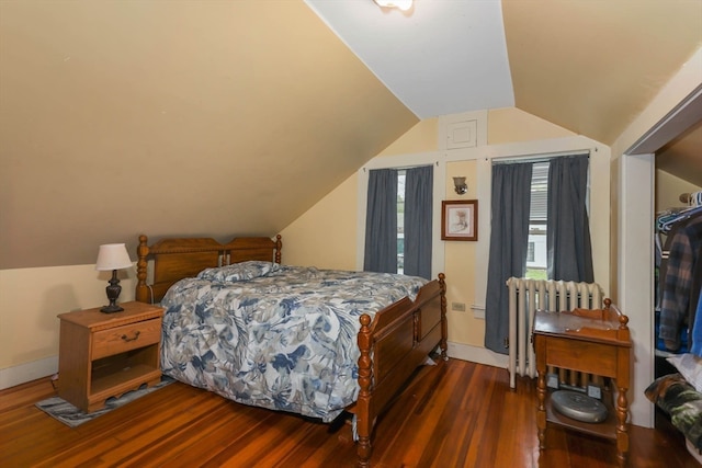 bedroom with a closet, vaulted ceiling, hardwood / wood-style floors, and radiator heating unit