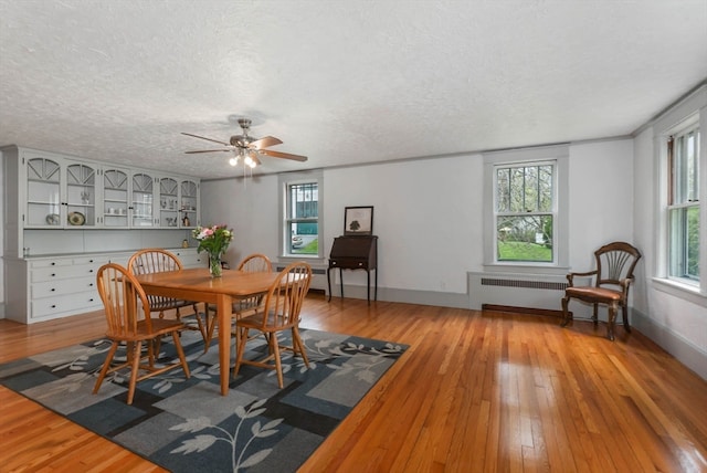 dining space featuring ceiling fan, plenty of natural light, radiator heating unit, and hardwood / wood-style floors