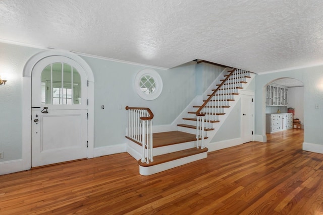 foyer entrance featuring ornamental molding, a textured ceiling, and wood-type flooring