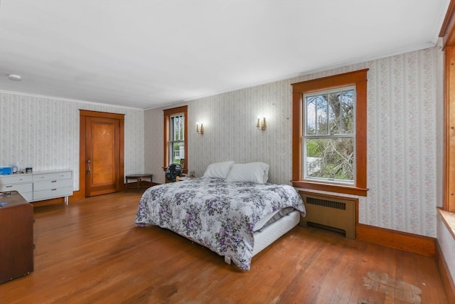 bedroom with hardwood / wood-style floors, crown molding, and radiator heating unit