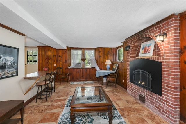 tiled living room featuring brick wall, a brick fireplace, a textured ceiling, and wood walls