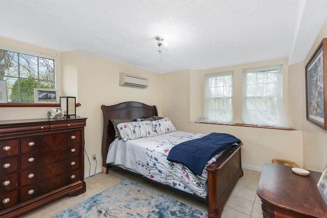 bedroom featuring a wall unit AC, multiple windows, a textured ceiling, and light tile flooring