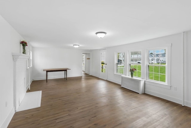 unfurnished living room with dark hardwood / wood-style floors and radiator heating unit