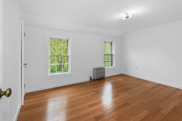 empty room with plenty of natural light, hardwood / wood-style flooring, and radiator