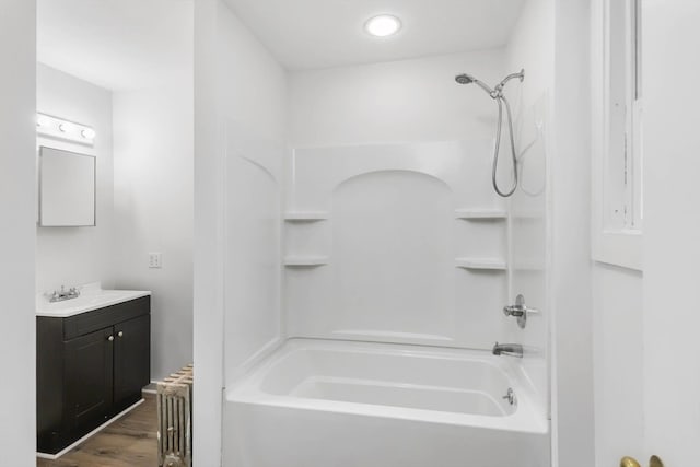 bathroom with hardwood / wood-style floors, vanity, and bathing tub / shower combination