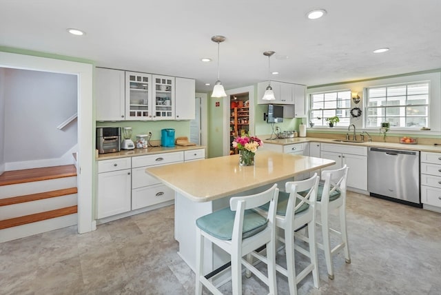 kitchen featuring white cabinetry, a kitchen bar, and stainless steel dishwasher